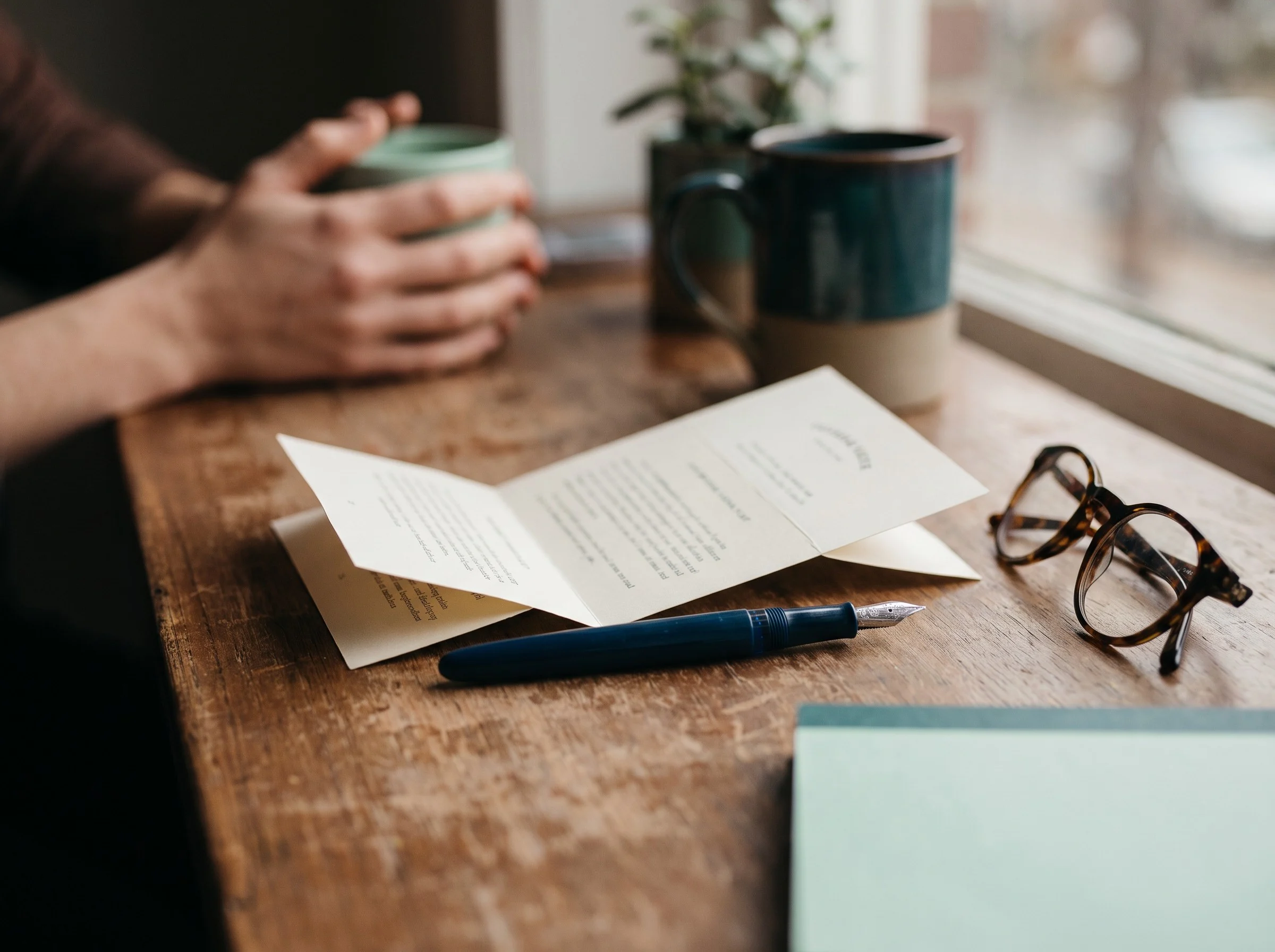 Patient leaflet, glasses and a mug on a wooden desk